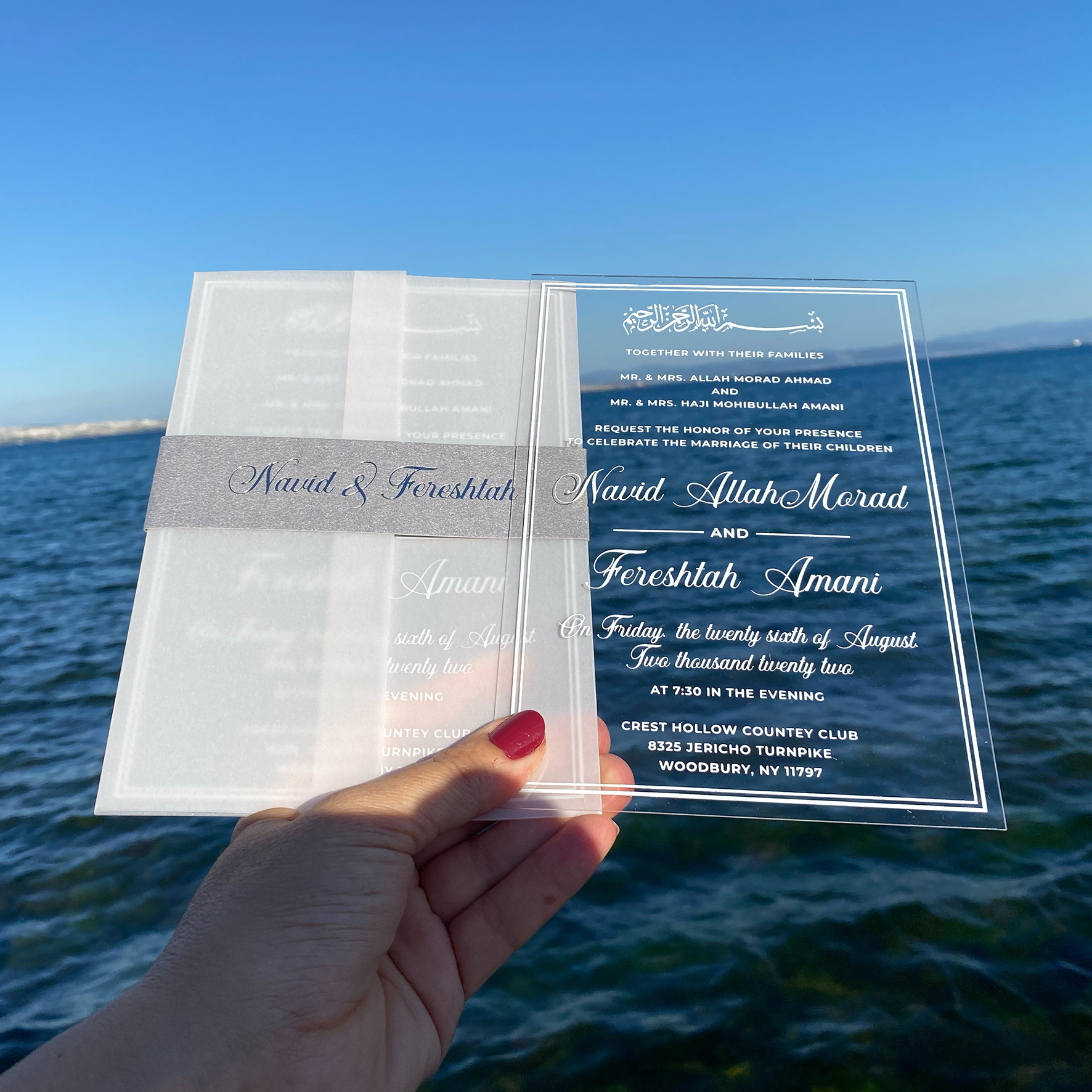 White printed clear acrylic wedding invitation. Parchment wrapping. Belly band with silver foil print. White mailing envelope. 